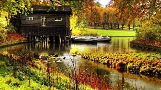 An autumn boathouse and rowing boats on still water